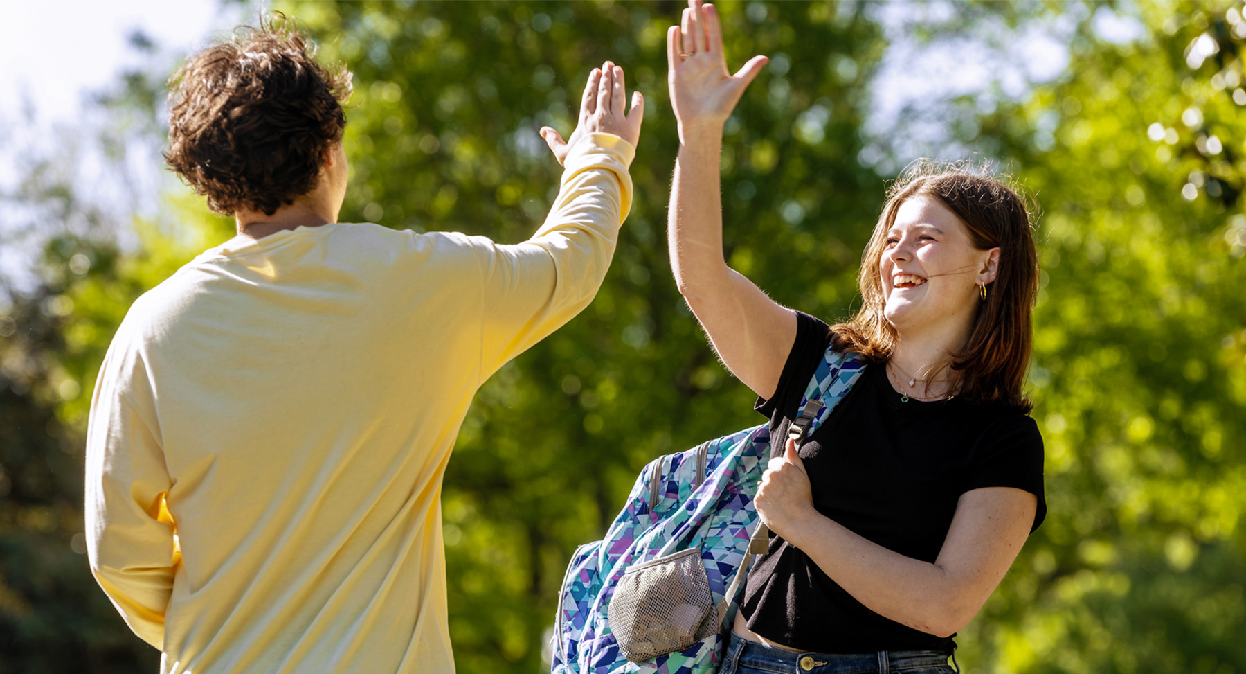 Students high fiving outdoors
