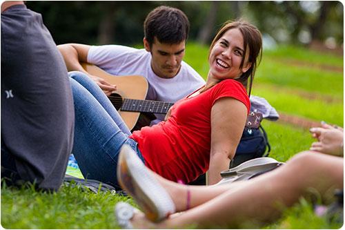 Smiling students with a guitar outside