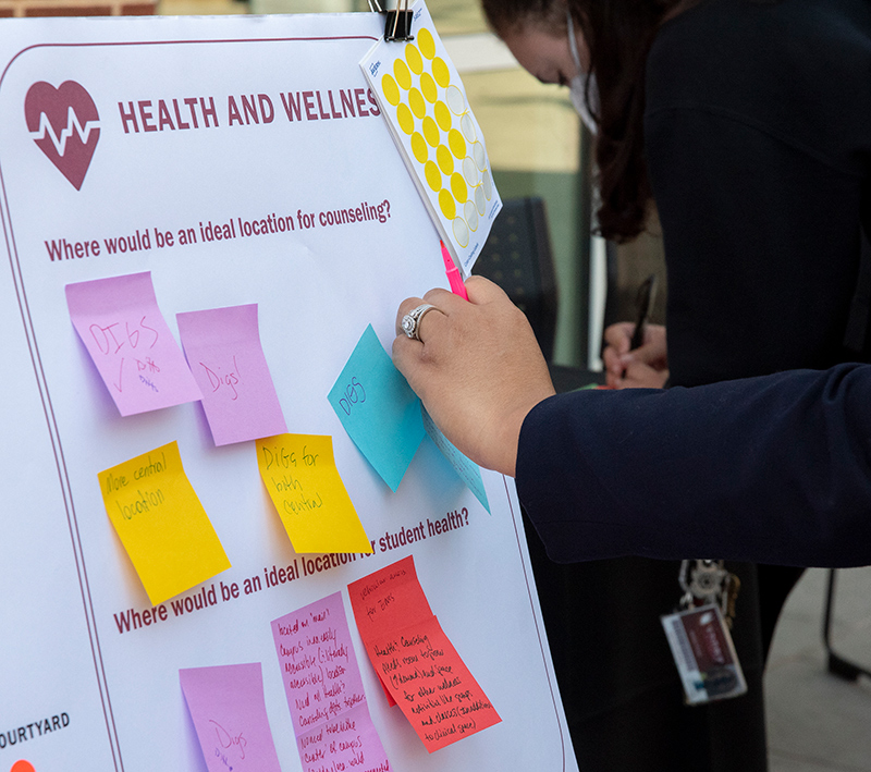 Student adding notes to a poster