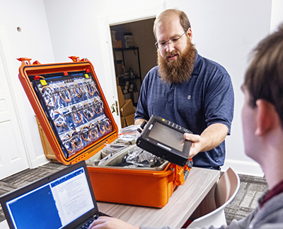 A professor and student working on computer hardware together.