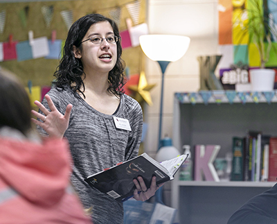 a student teacher reading to a group of young children.