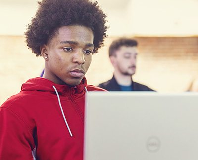 A student taking notes on his laptop during class.