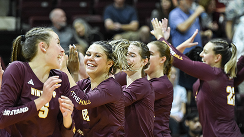 Volleyball players celebrating and high-fiving each other
