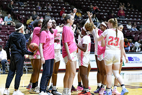 Women's basketball players in a huddle on the court