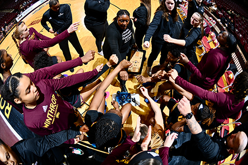 Women's basketball players in a huddle on the court