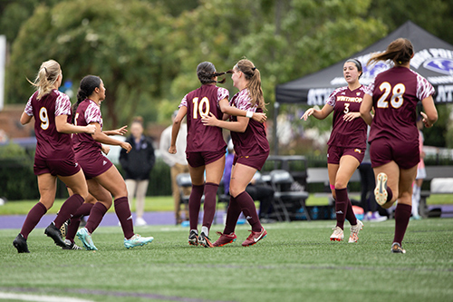 Women's soccer players celebrating after a goal