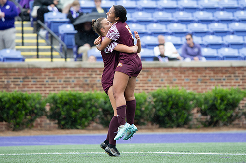 Two soccer players hugging after scoring a goal