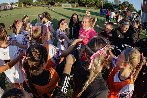 Women's soccer players in a huddle on the field