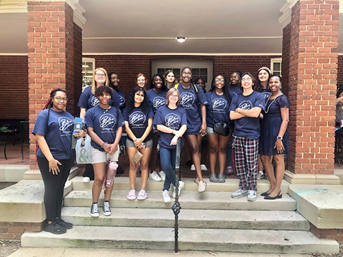 A group photo of Social Work students in matching blue shirts standing on the steps
                        of Bancroft Hall