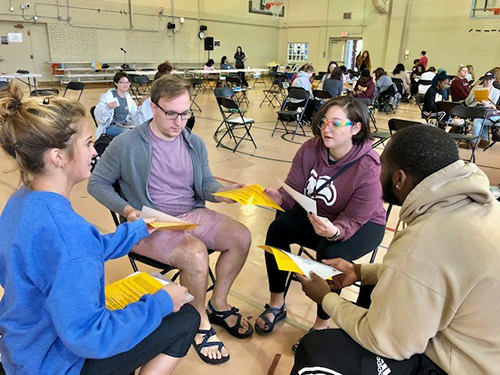 Four Social Work students sitting in a circle doing a poverty simulation activity