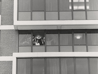 Women waving from an open glass window