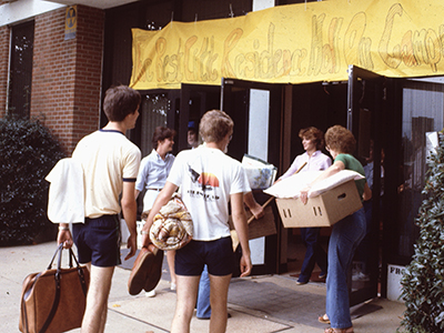 People holding boxes and bags walking into a building
