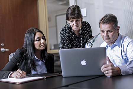 woman pointing at laptop with two colleagues