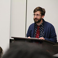 A student reading his work from a lectern