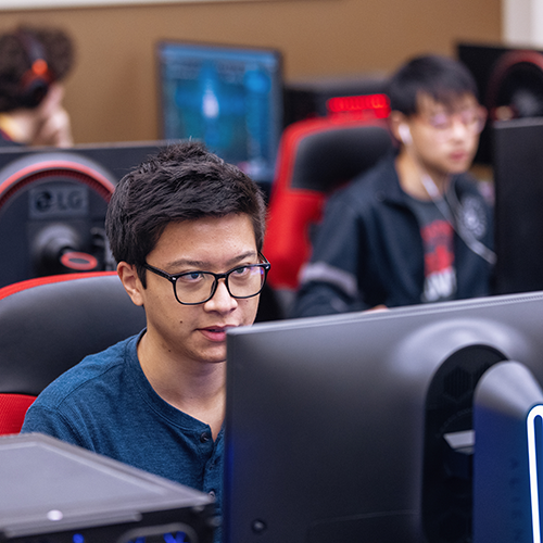 Three members of the Winthrop esports team focusing on their computer screens while
                     practicing