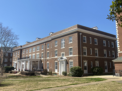 Brick building with wide white front porch and no construction fence around it