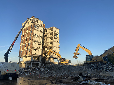 Remains of tall brick building in front of a blue sky and debris pile