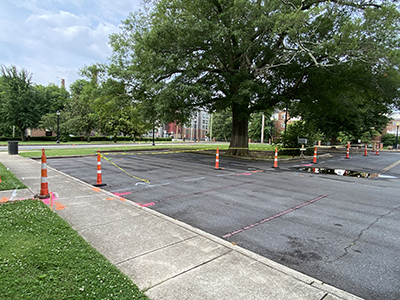 Orange construction cones and yellow tape marking off sections in a paved parking
                        lot