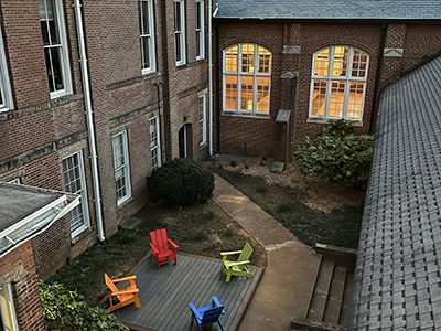 Colorful chairs facing each other on a patio in a courtyard surrounded by brick buildings