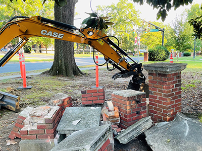 Brick columns broken in pieces with a construction tool near them
