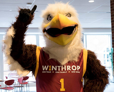 big stuff eagle mascot wearing a winthrop jersey and holding one finger up