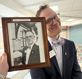 Dean Grossoehme posing with a black and white photo of himself that has pink blush
                        applied