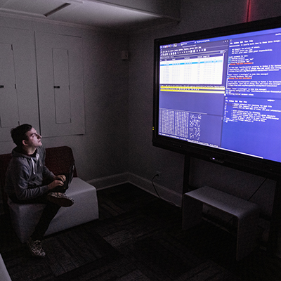 Student writing code on large screen monitor