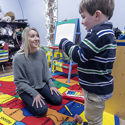 A student interacting with a preschool child in the classroom