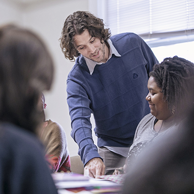 A professor speaking to a student in a classroom