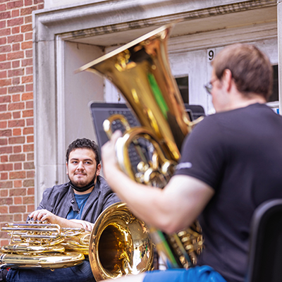 Brass players sitting outside with their instruments.