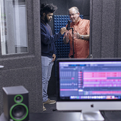 A professor talking to a student in a recording studio.