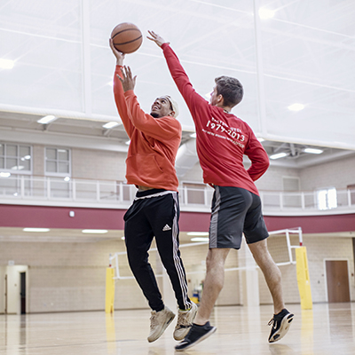 Two students playing basketball in the gym