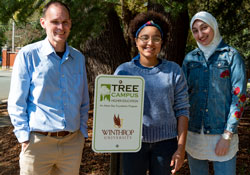 Chris Johnson, from left, students Bobbie Owen and Juman Nouh with new Tree Campus sign