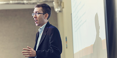 a professor lecturing in front of a projector screen
