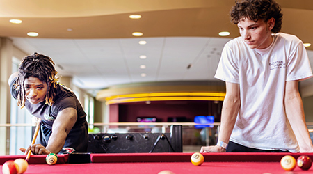 two students playing pool in the digiorgio student center