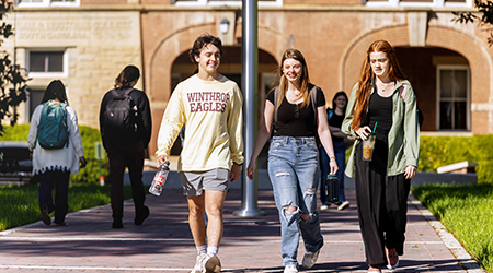 three students walking together in front of tillman hall