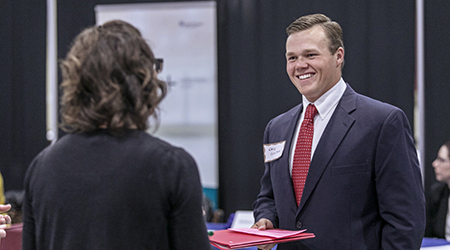 Two people in business attire networking at a conference