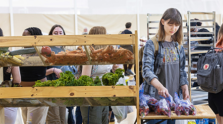 a student looking at fruits and vegetables at a farmers market event on campus