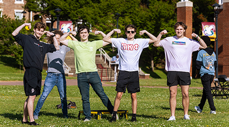 a group of students flexing on campus green
