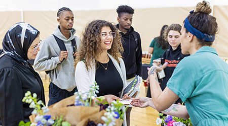 a student buying fresh flowers at a farmers market event