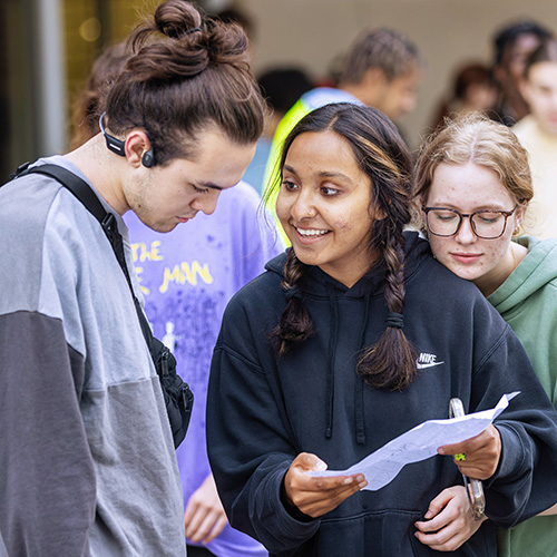 three students looking at a piece of paper together