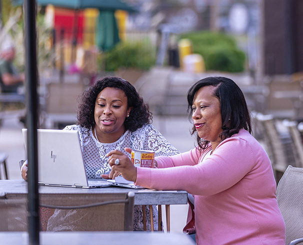 two women working on a laptop together at a coffee shop