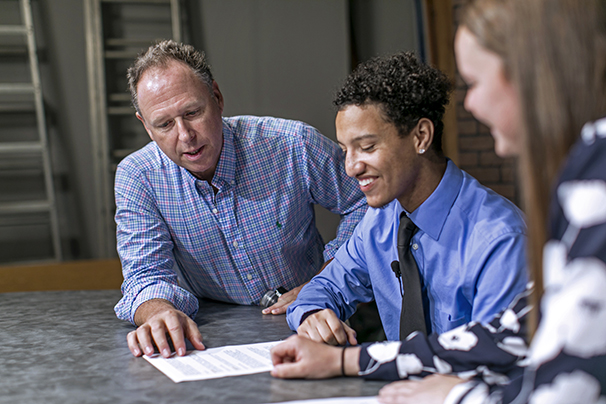 a professor giving advice to a mass comm student in a suit before he goes on camera
