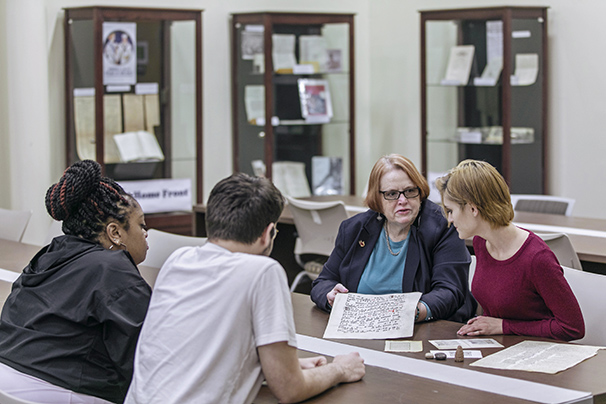a professor showing her students a medieval document in the archives