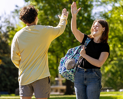 two students high fiving with smiles on their faces