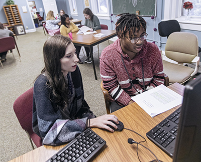 a tutor working with a student on his paper in the writing center