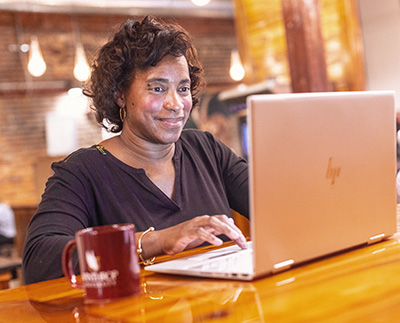 a senior citizen student studying with her laptop at a coffee shop