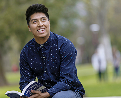 a student sitting outside reading a book