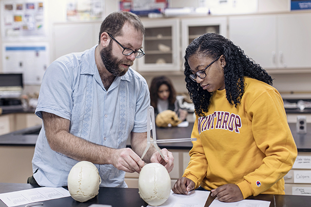 an anthropology professor and student looking at a skull in a lab