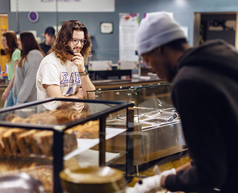 a student deciding which food to select at the Eagle Eatery cafeteria
